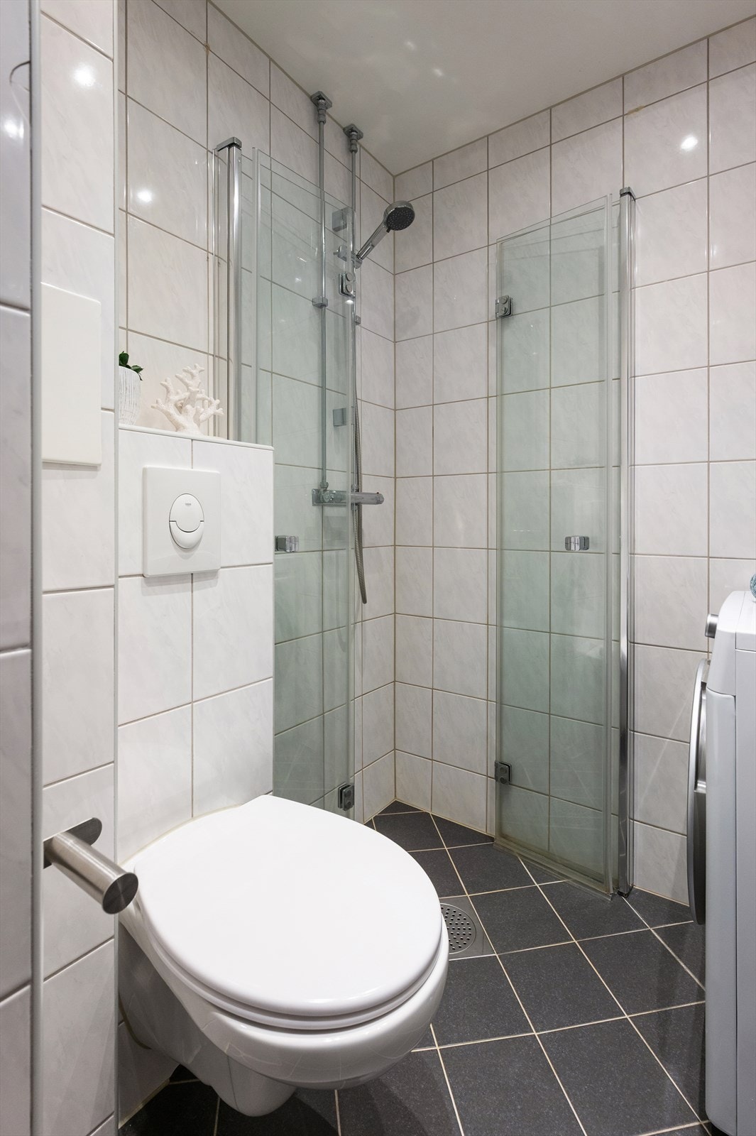 Vegghengt toalett, gulvet er flislagt med varmekabler, vegger er flislagt, og himling er malt med downlights. Galleribilde