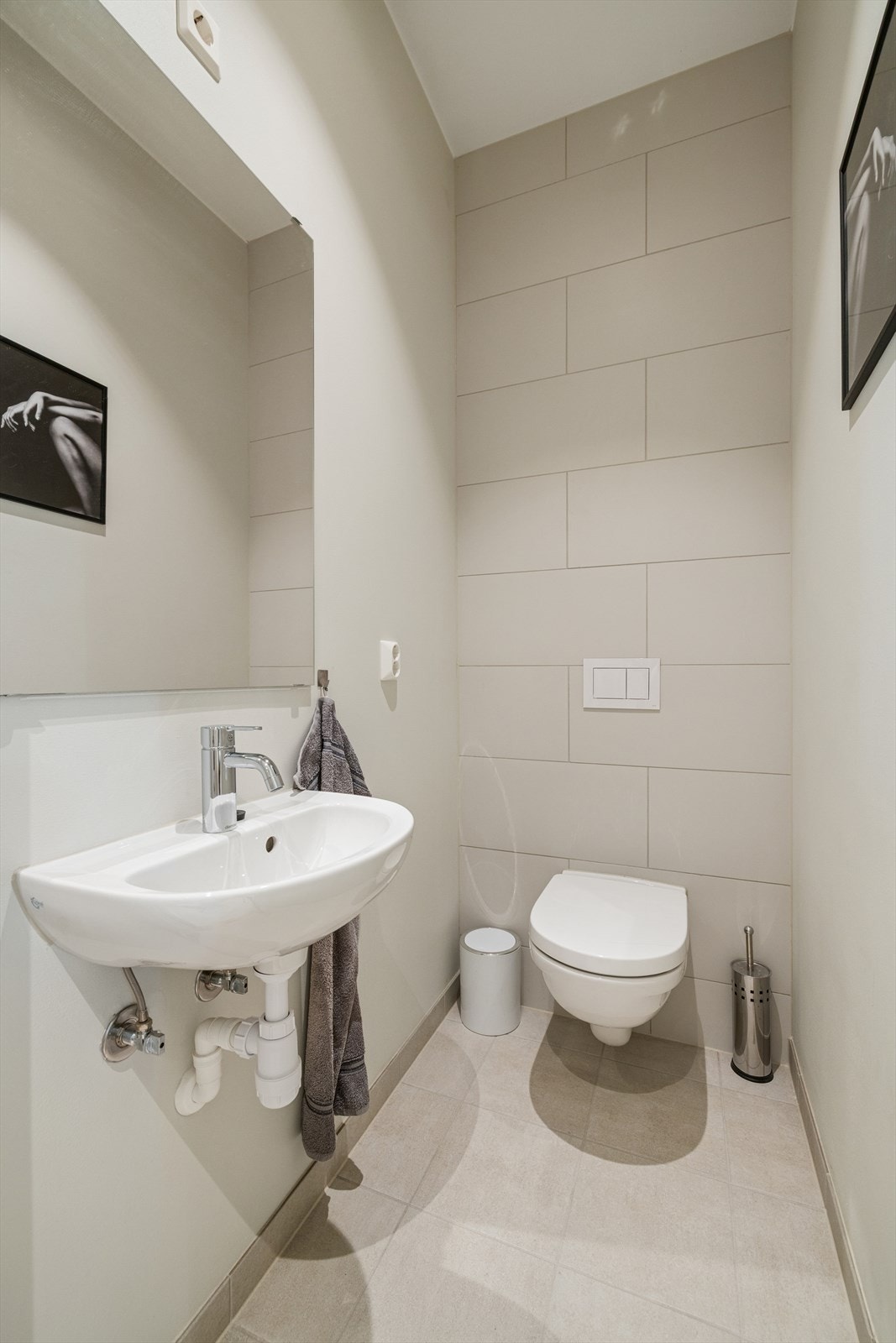 Leiligheten har videre et eget toalettrom som er praktisk innredet med vegghengt toalett, speil og servant. Rommet er gjennomført med fine fliser på gulvet, samt en kombinasjon av fliser og malte veggflater. Galleribilde