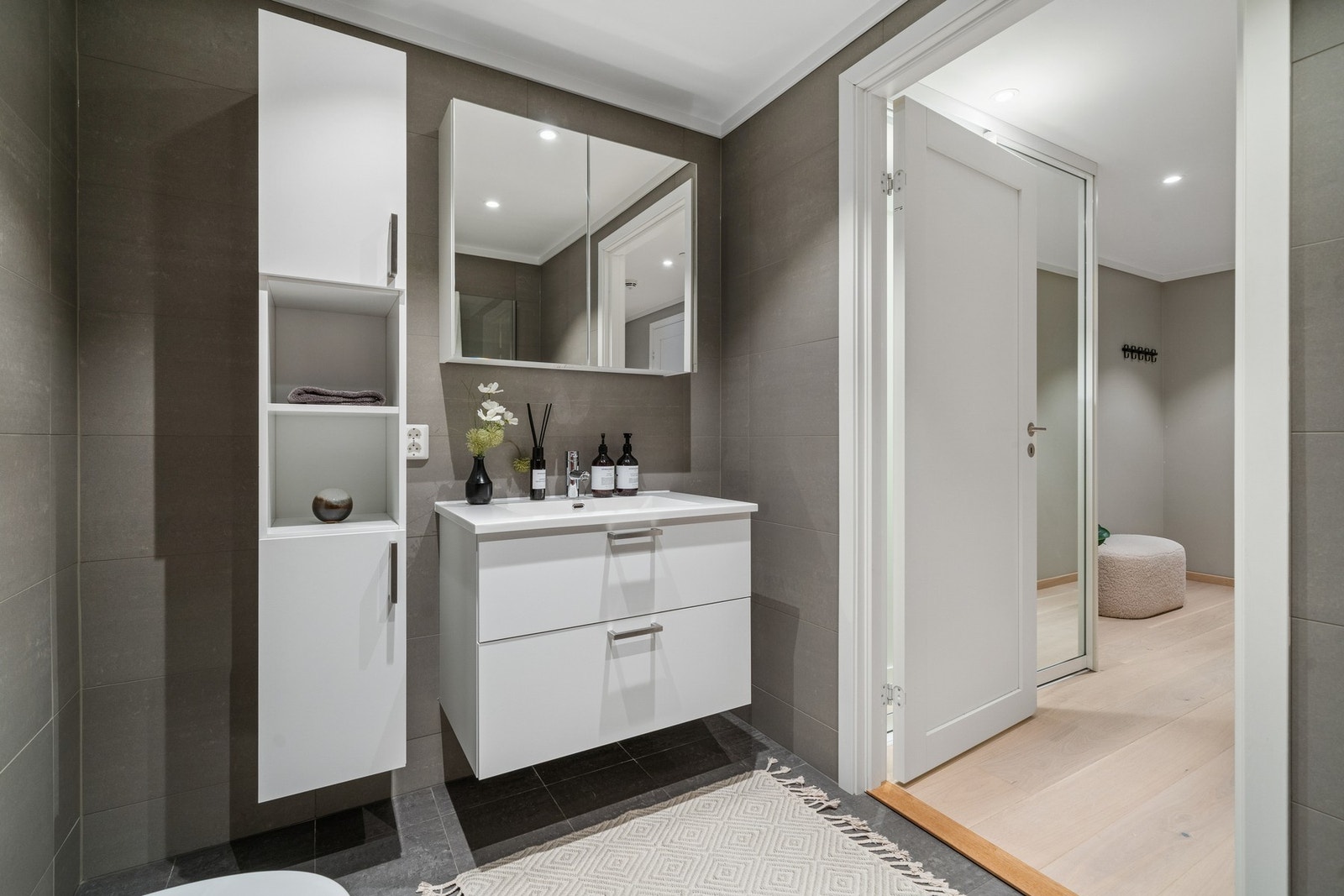 Badet er praktisk plassert med adkomst fra gang og nærhet til soverommene. Moderne innredning, speilskap og servant med oppbevaringsskuffer gir god funksjonalitet i hverdagen. Galleribilde