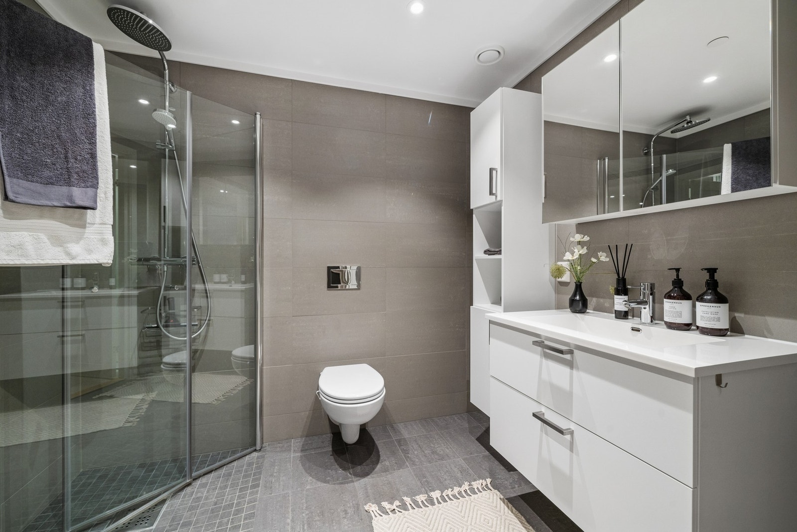 Flislagt bad med dusjhjørne, vegghengt toalett og moderne innredning. God plass og praktisk løsning med speilskap og servant med oppbevaringsskuffer. Dokumentert membran og fall til sluk sikrer trygg bruk. Galleribilde