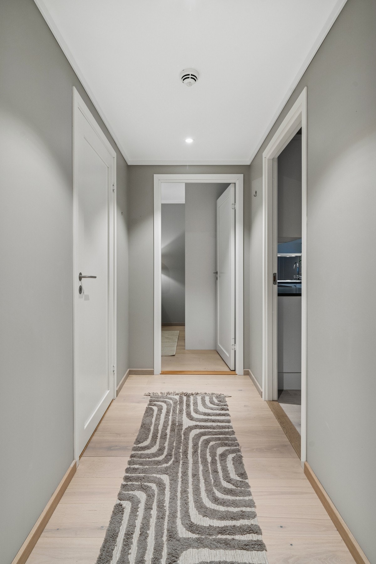 Boligen har en romslig soveromsgang med lyse overflater og gjennomgående parkettgulv. God plass til oppbevaring og tilgang til alle boligens rom fra samme sone. Galleribilde