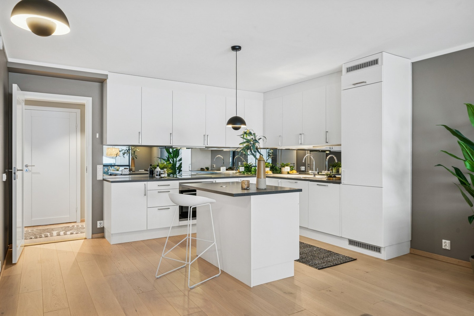 Kjøkkenet har rene linjer, glatte hvite fronter og slitesterk benkeplate i laminat. Speilflis over benken gir romfølelse og et moderne uttrykk. Galleribilde