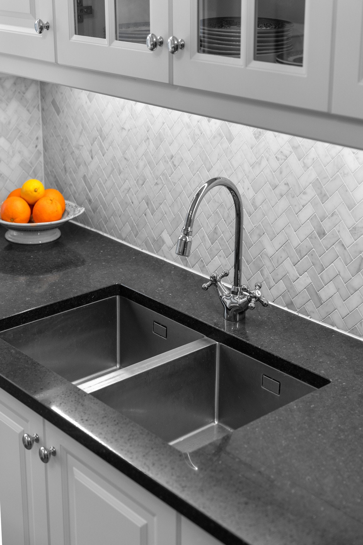 Lyse marmorfliser i fiskebensmønster og mørk
komposittstein benkeplate Galleribilde