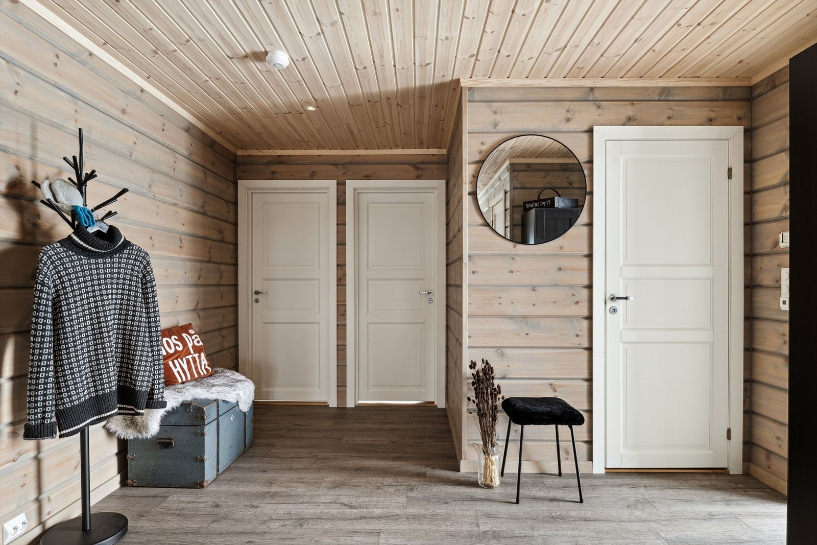 Når du entrer hytta kommer du inn i en lys og innbydende entré. God standard fra 2021 med enstavs laminat på gulv med gulvvarme, overflater med liggende panel og downlights i himlingen. Plass til sko og yttertøy i medfølgende garderobeskap. Galleribilde