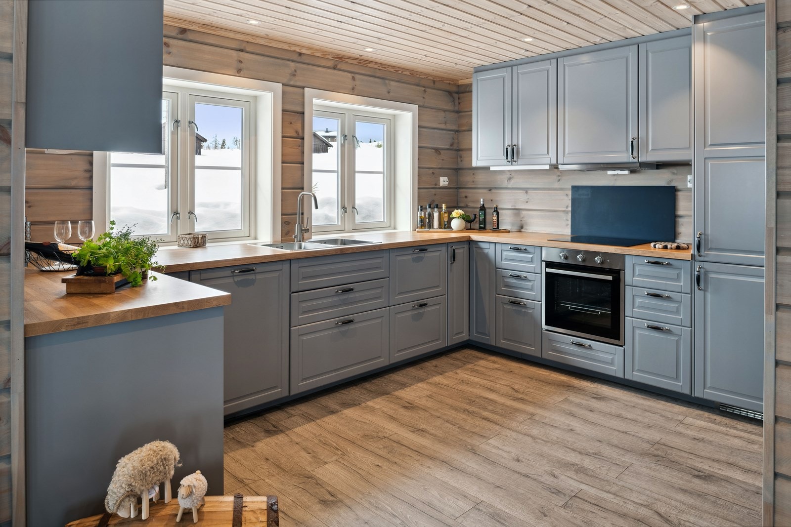 Du har god skap- og benkeplass i innredningen som har grå profilerte fronter og laminert benkeplate med nedfelt oppvaskkum. Praktisk med takhøye overskap, plate i benkeryggen ved platetoppen og god belysning med downlights i himlingen. Galleribilde