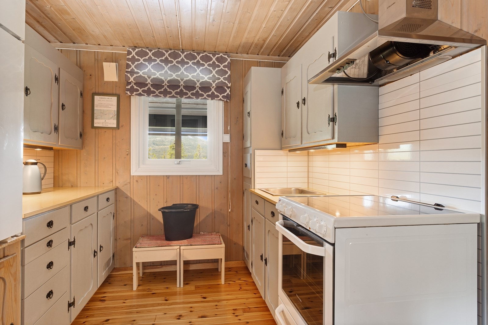 Tradisjonell innredning med profilerte, lyse fronter og laminert benkeplate med nedfelt oppvaskkum. Galleribilde