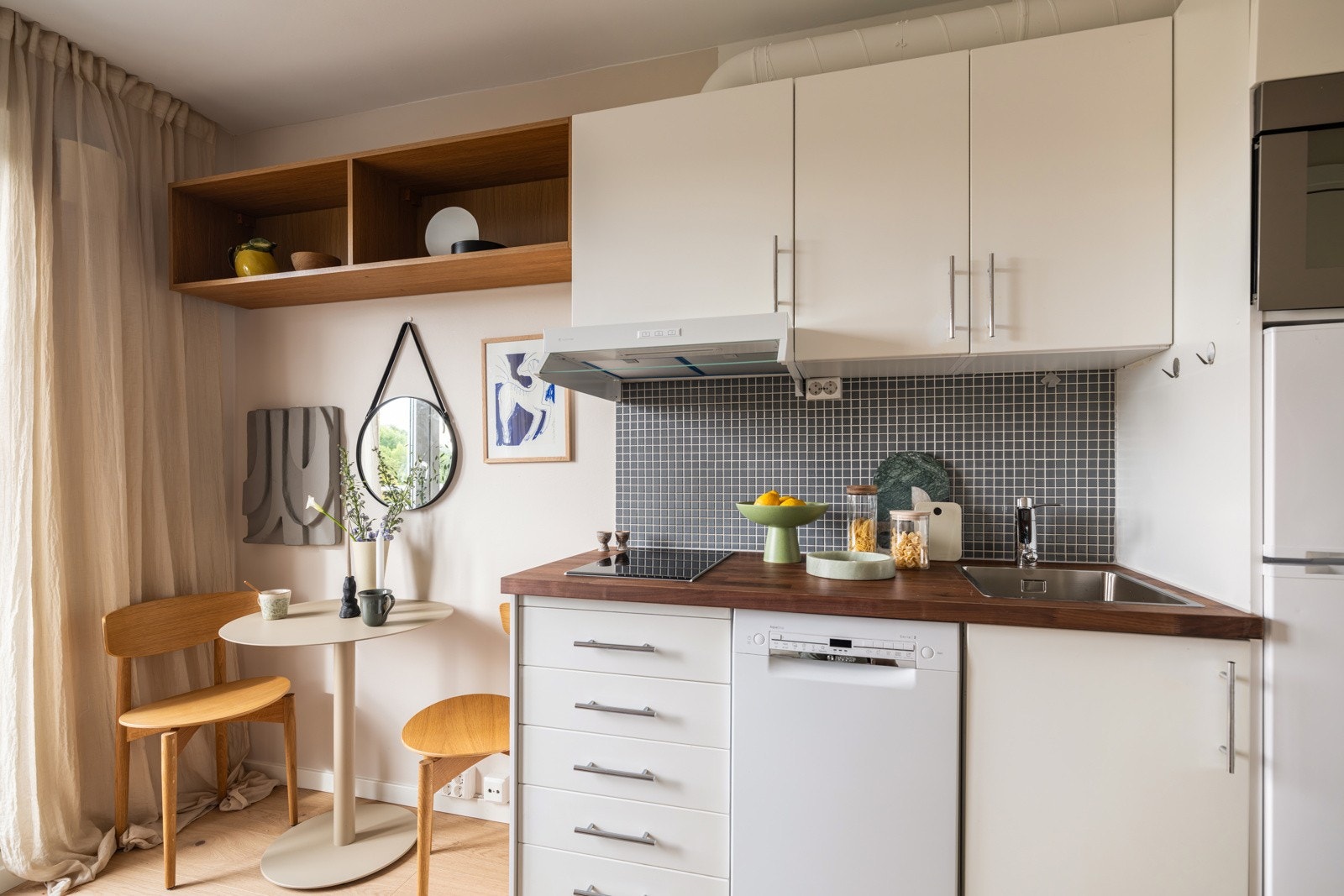 Lys og pen kjøkkeninnredning fra 2008 med hvite glatte fronter og laminert benkeplate med nedfelt oppvaskkum. Galleribilde