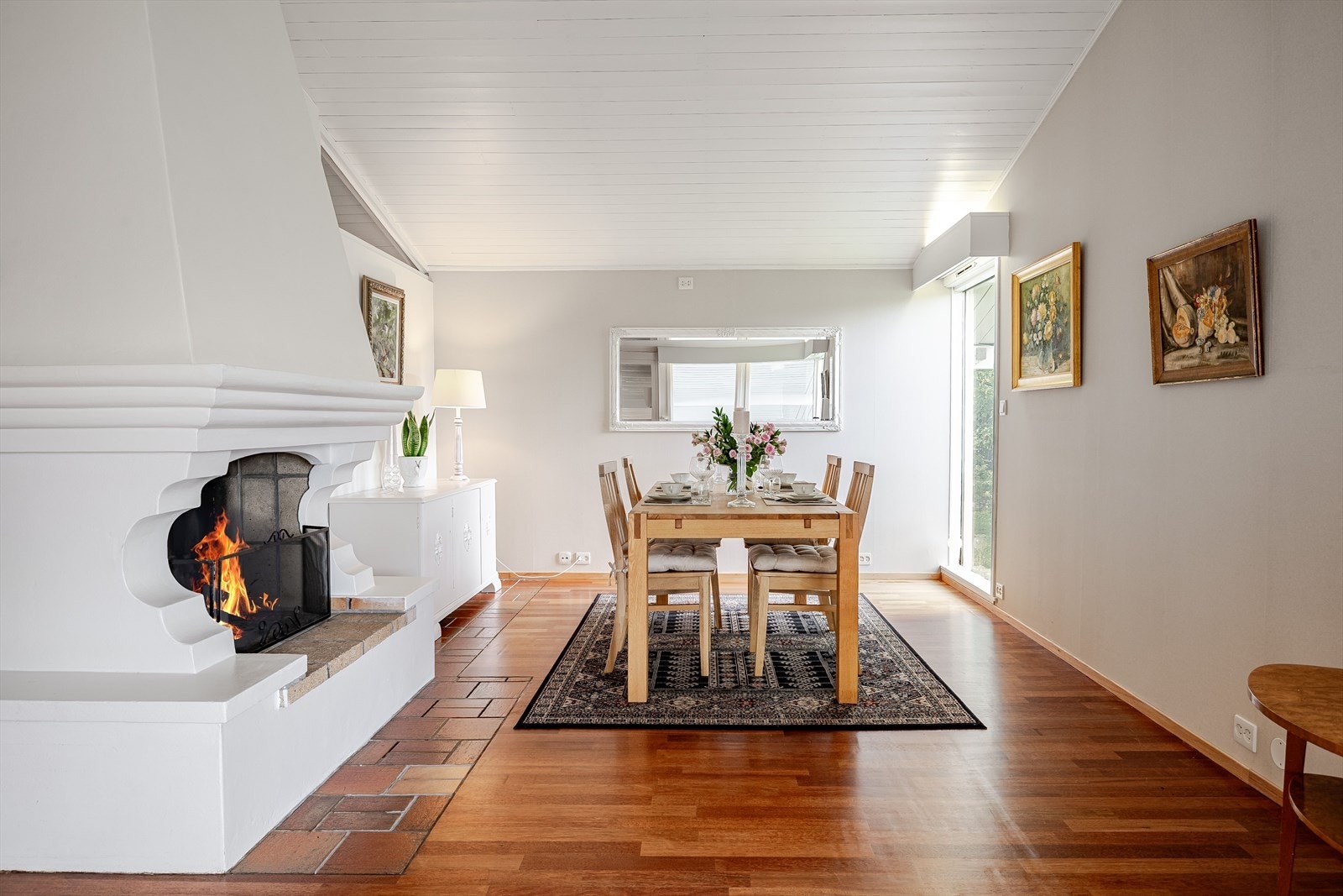 Spisestuen ligger på samme plan som kjøkkenet og har en flott åpen peis. Her kan du invitere venner og familie på hyggelige selskap foran peisen. Du kan også dekke opp til fest med et ordentlig langbord! Galleribilde