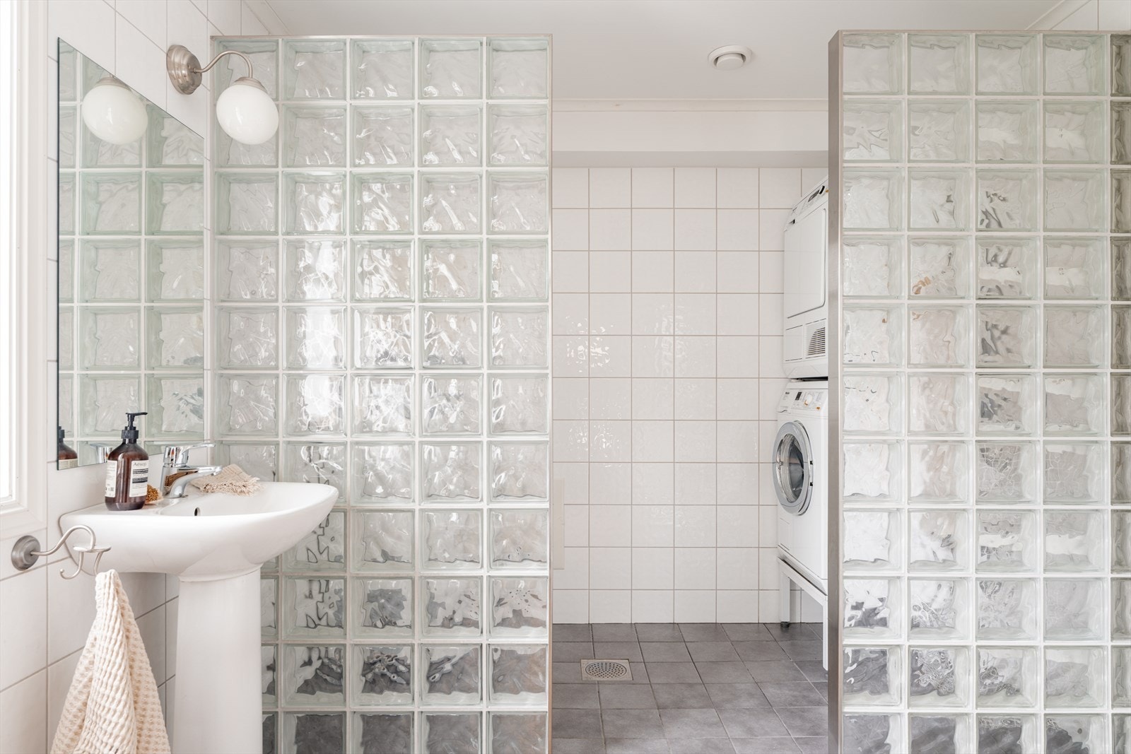 Glassbyggerstein skiller mellom bad- og vaskesonen, og det er to sluk - ett i dusjen og ett i vaskesonen. Galleribilde