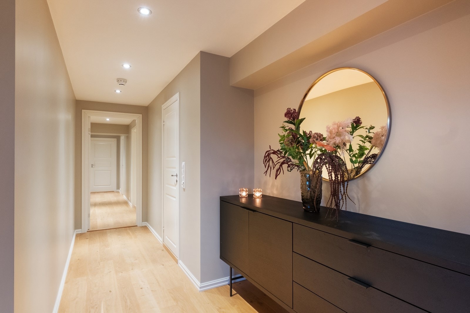 Lyssettingen i gangen fremhever de slettmalte veggene og gir god belysning gjennom rommet. Galleribilde