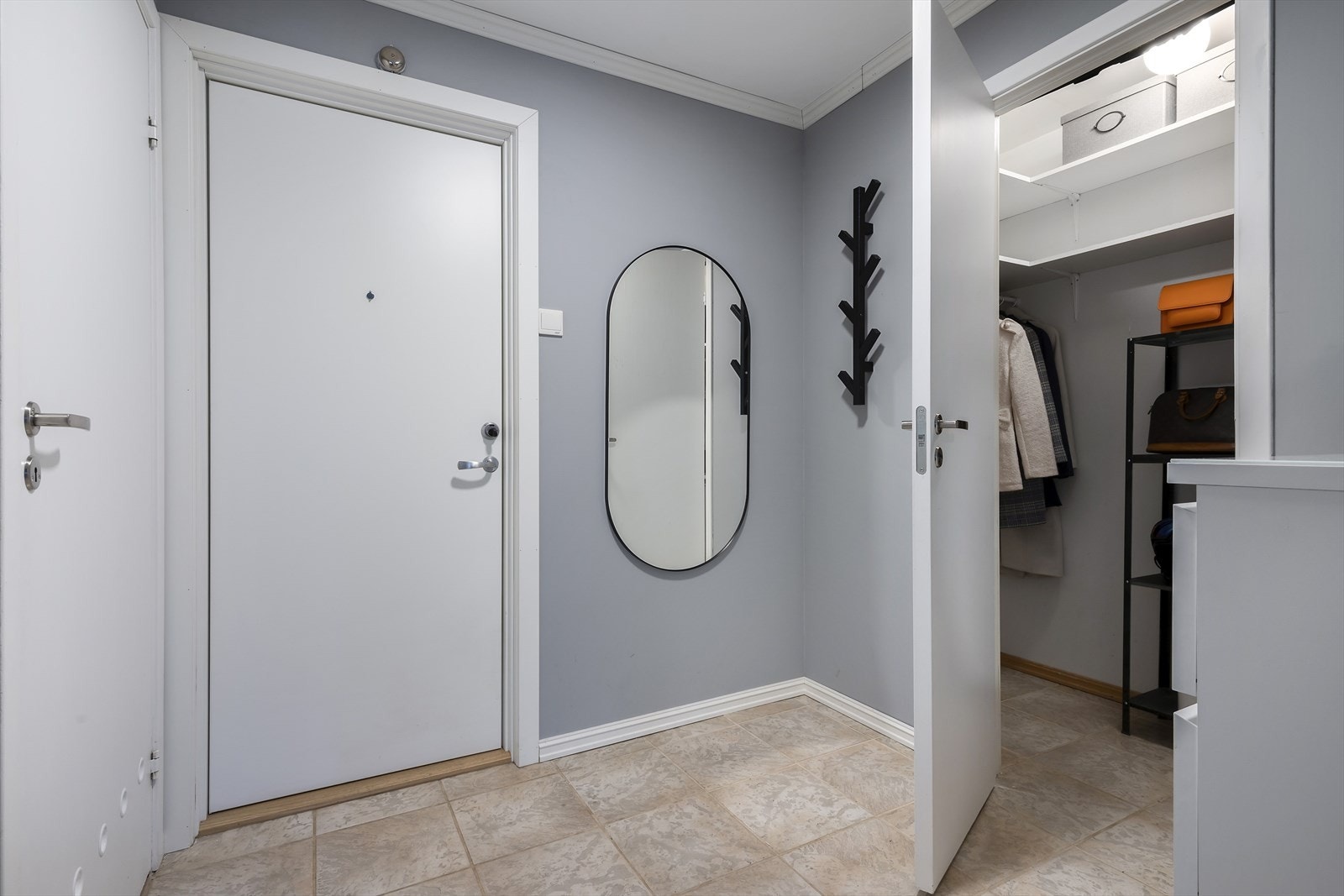Romslig entré med flislagt gulv, malte veggflater og plass for oppbevaringsmøblement Galleribilde