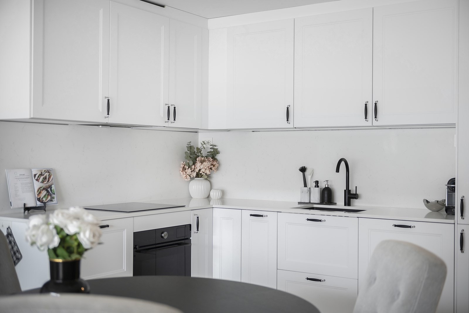 Delikat og tidløst kjøkken fra 2024 med integrerte hvitevarer og plass for spisebord Galleribilde