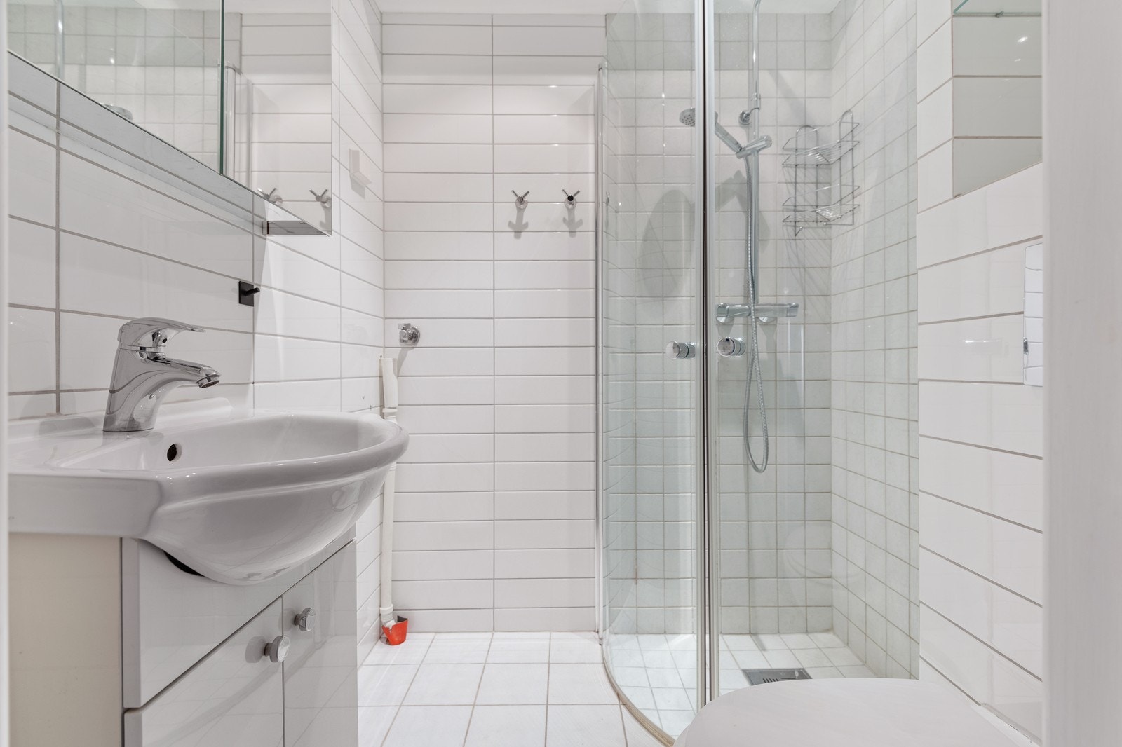 Lyst og trivelig baderom med dusj, WC og servant med underskap. Galleribilde