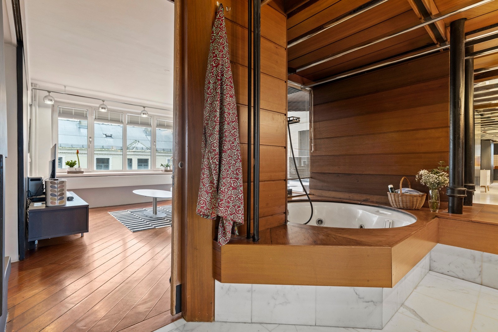 Her er det et badekar med innrammet oppbygging samt vinduer rundt deler av karet, som gir utsyn mot tv-stuen. Galleribilde