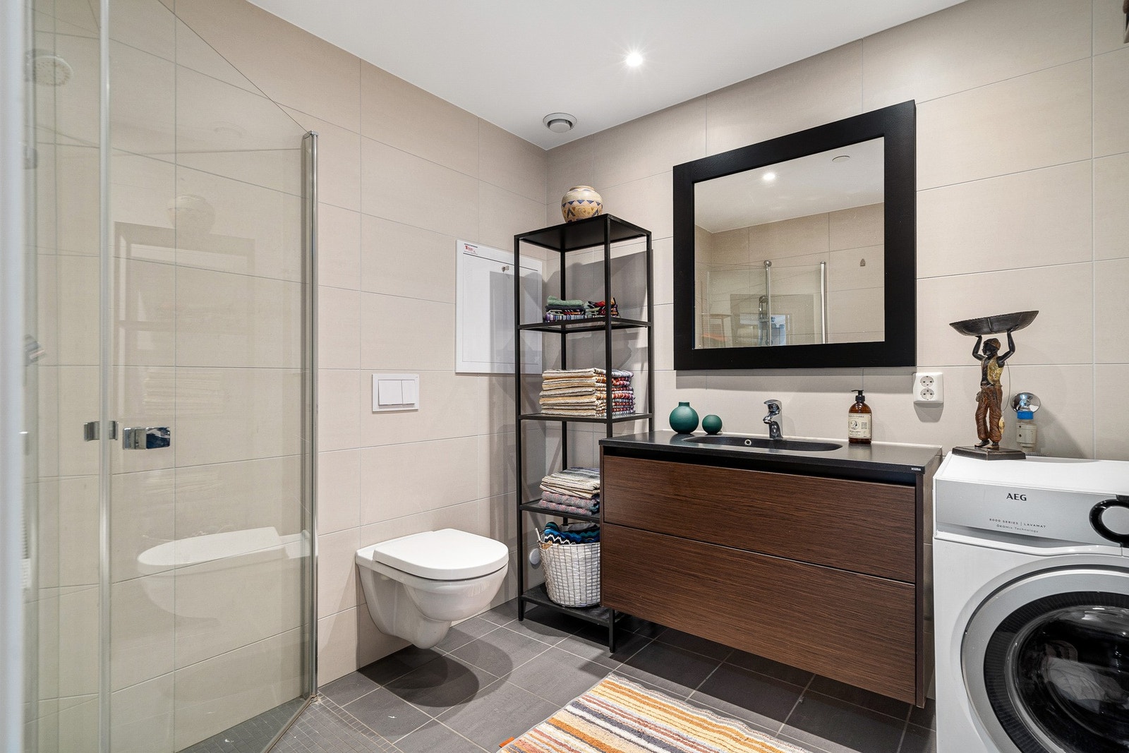 Romslig bad med dusj i hjørne, servant med underliggende skuffer og vegghengt toalett Galleribilde