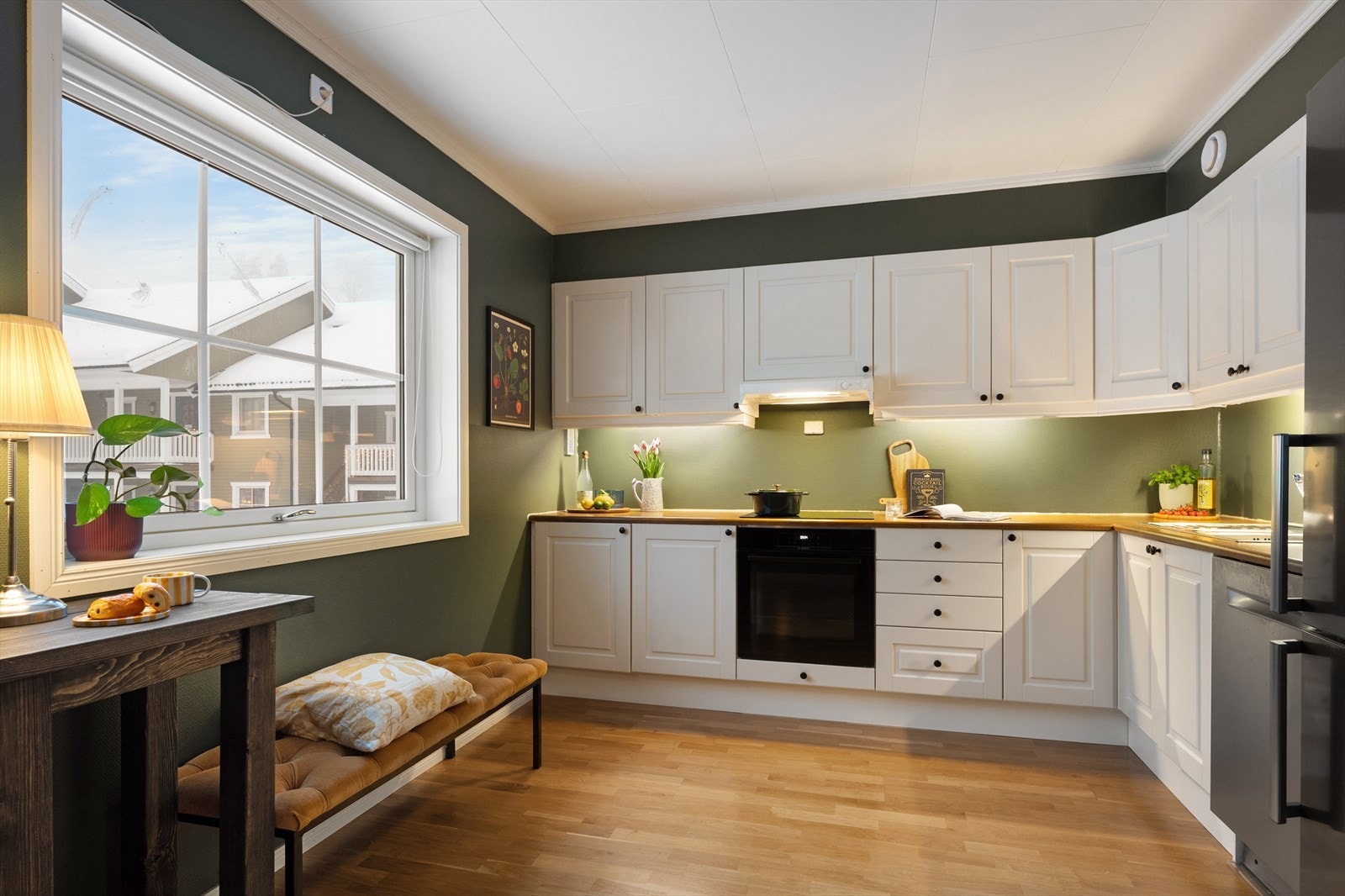 Kjøkkenet har en klassisk og tidløs utforming med kjøkkeninnredning bestående av profilerte hvite fronter. Benkeplaten er i laminat og det er nedfelt vaskekum i børstet stål, med ettgreps krummet armatur fra Gustavsberg. Galleribilde