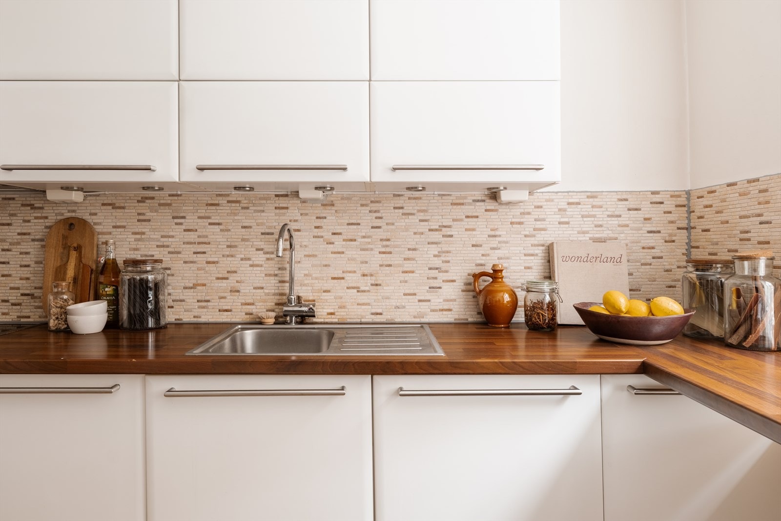 Hvit, glatt kjøkkeninnredning med laminert benkeplate og nedfelt oppvaskkum med 1-greps blandebatteri. Galleribilde