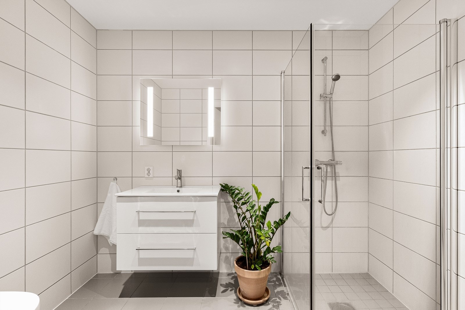 Delikat og moderne bad med flislagt gulv med varmekabler og flislagte vegger som gir et stilrent og tidløst uttrykk. Galleribilde