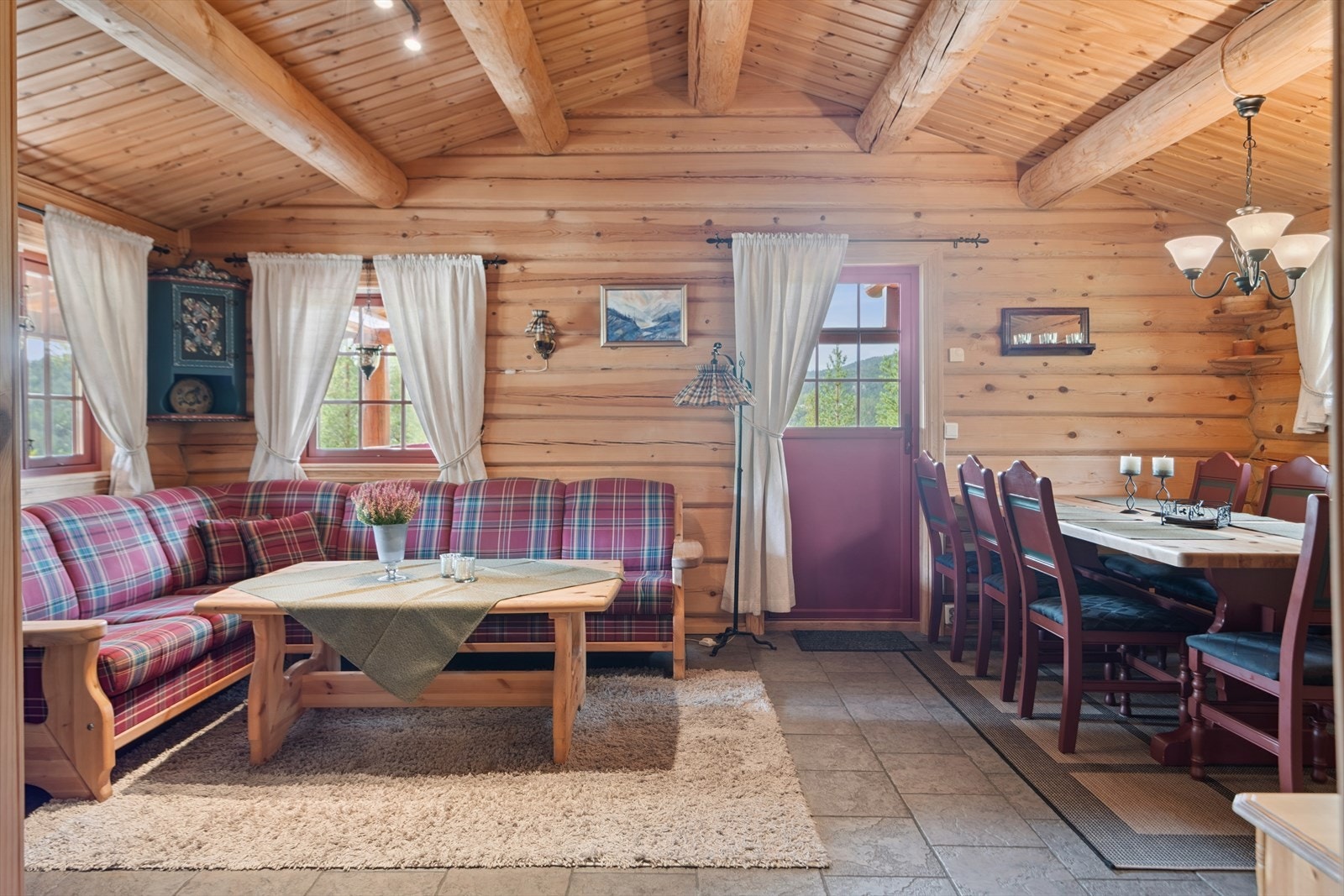 Delvis åpen stue- og kjøkkenløsning med synlige takåser som skaper en luftig atmosfære. Galleribilde