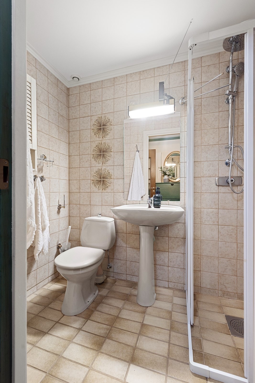 Flislagt dusjbad med toalett i tilknytning til inngangspartiet i hovedetasjen Galleribilde