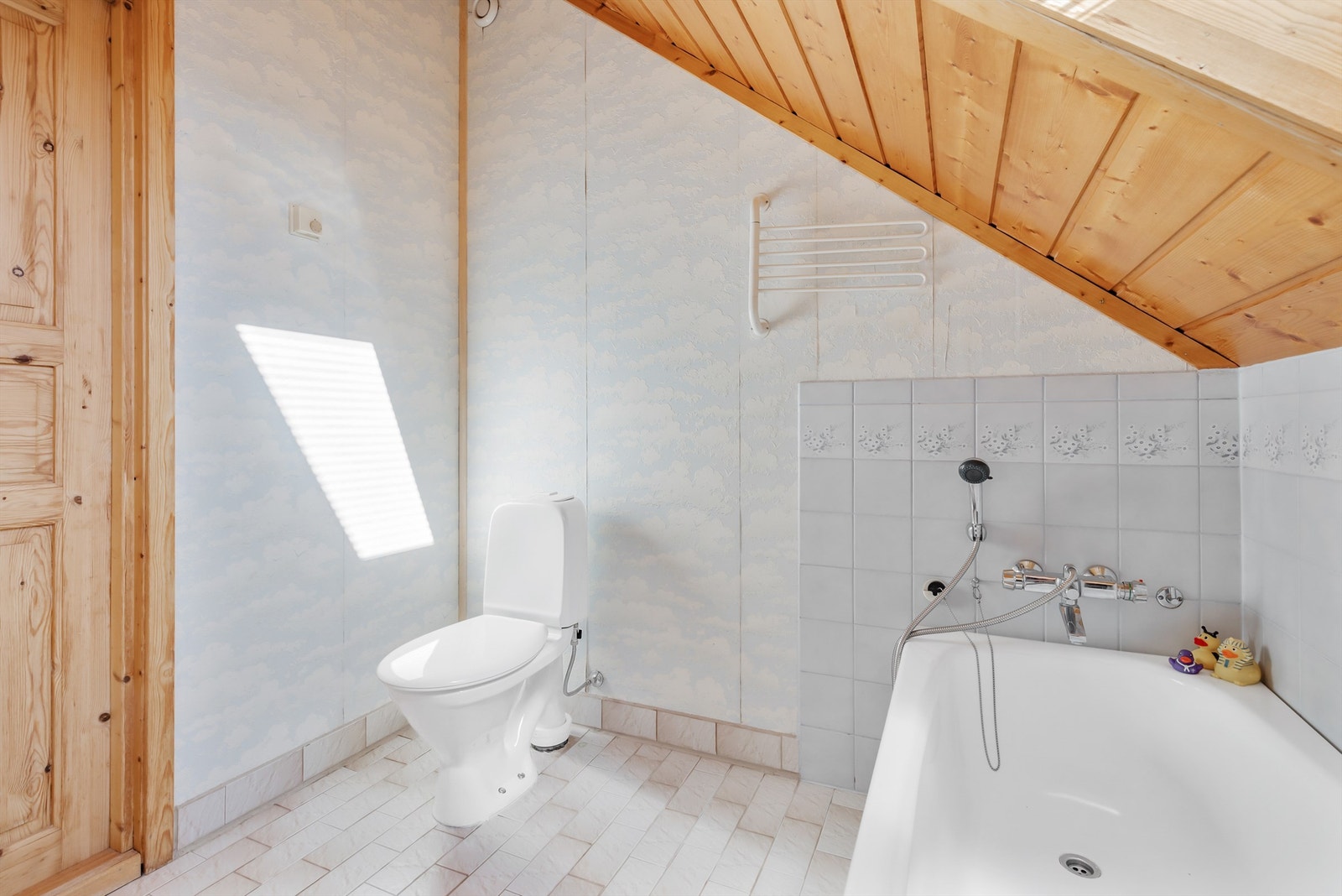 Flislagt gulv med varme. Veggflater med tapet og fliser ved badekaret. Himling/skråtak med panel. Galleribilde