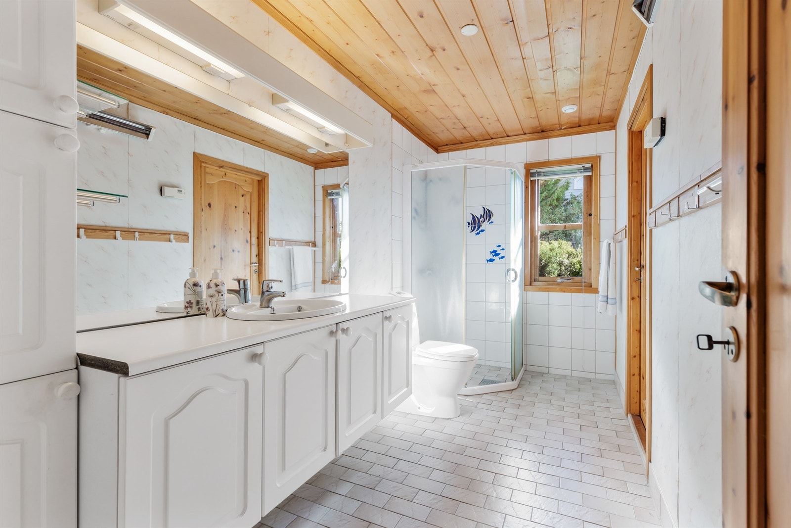 Vegghengt servantskap med profilerte fronter. Benkeplate med laminert flate. Nedfelt servant med ett-greps armatur.
Speil og overlys med stikkontakt på vegg over servant.
Dusj på gulv i hjørnet med skyvedør. Galleribilde