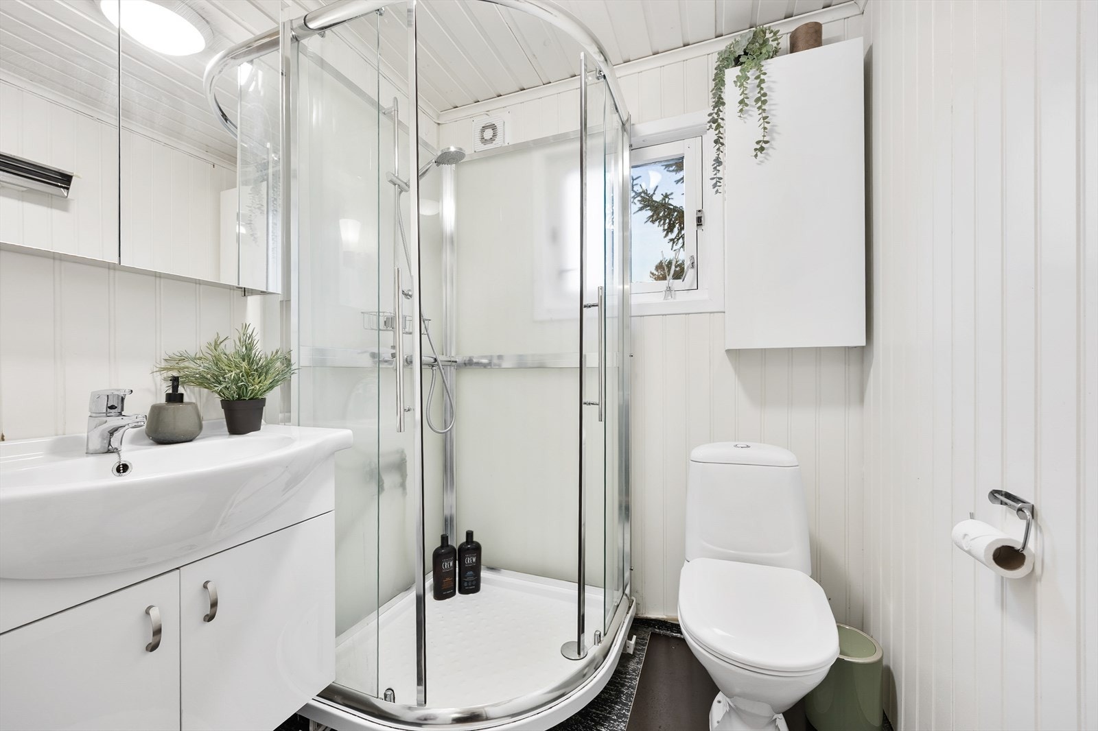 Badet er i hvitt og grått med panel på veggene og belegg på gulvet. Galleribilde