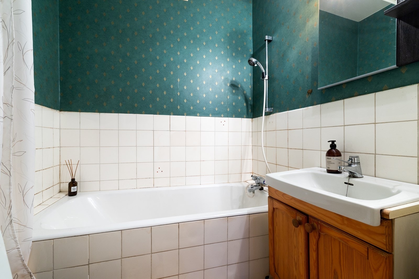 Eldre baderom som er flislagt og innredet med skap med glatte fronter og nedfelt servant. Galleribilde