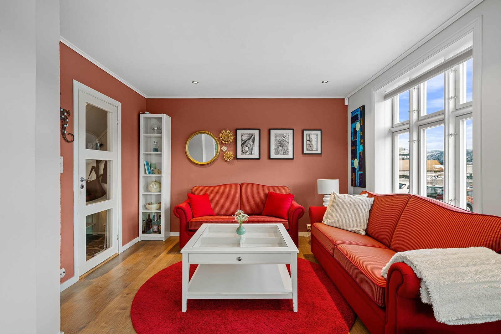 To av veggene i stuen er malt med en gyllen rødtone som gir en fin kontrast mot det hvite Galleribilde