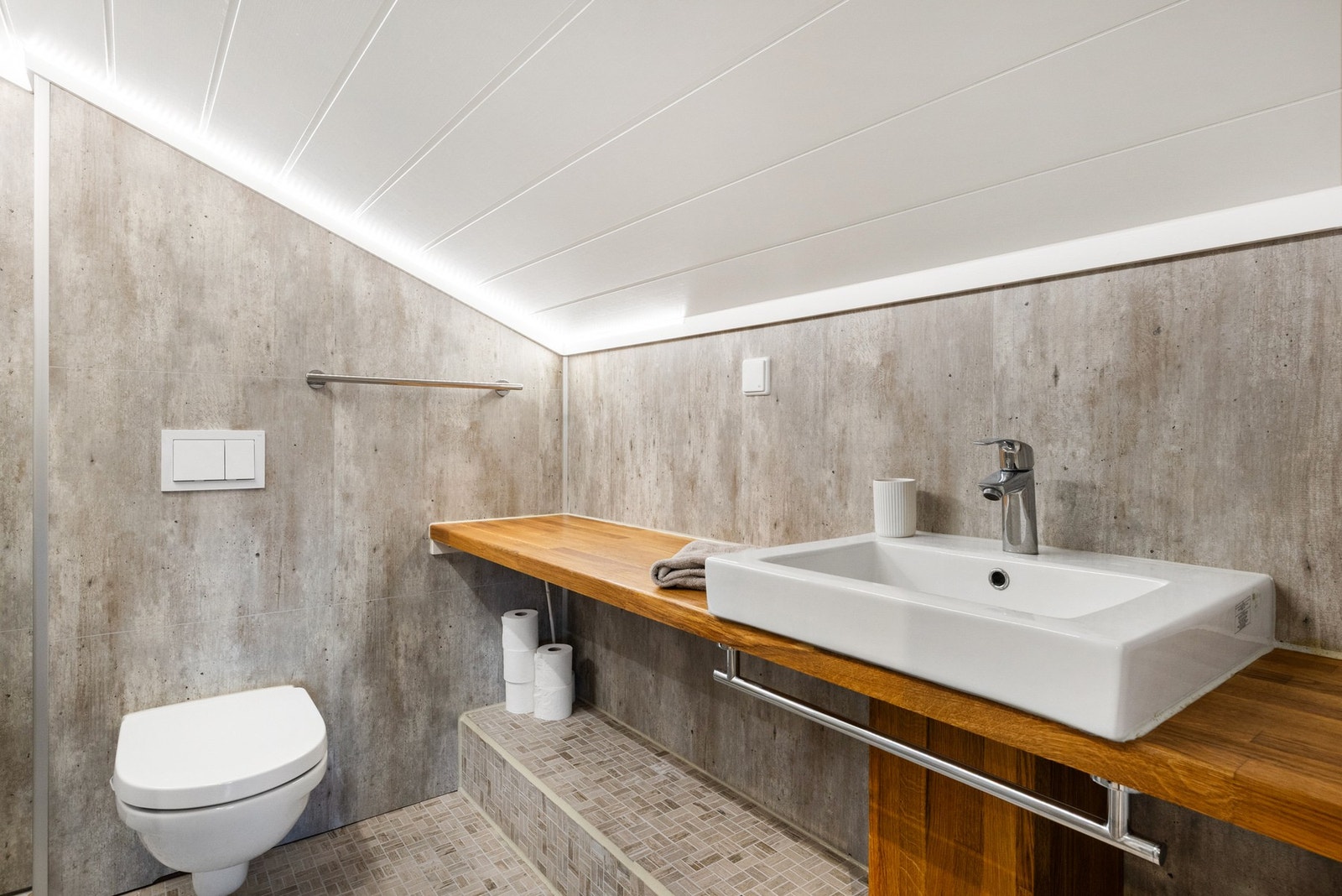 Loftbadet har innredning i heltre eik med benk og servant, som gir både funksjon og varme til rommet Galleribilde