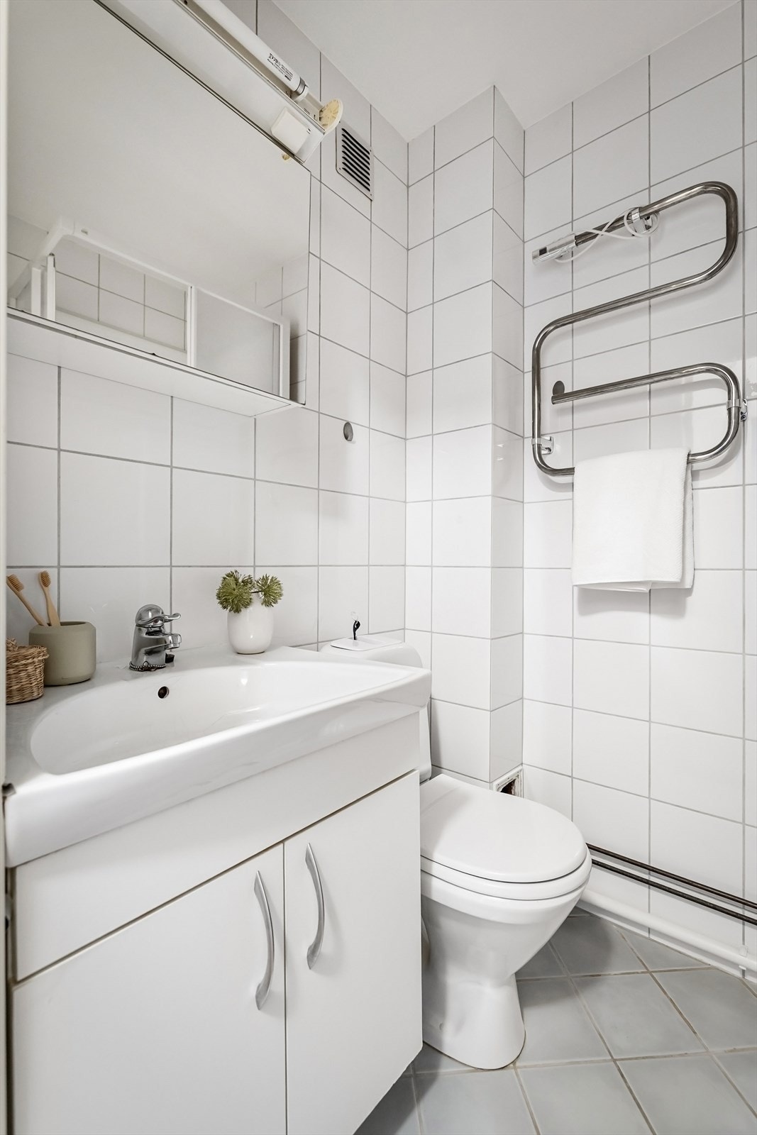 Innredet med gulvstående toalett, vegghengt servant med skap under, speilskap med belysninger over og dusjkabinett Galleribilde