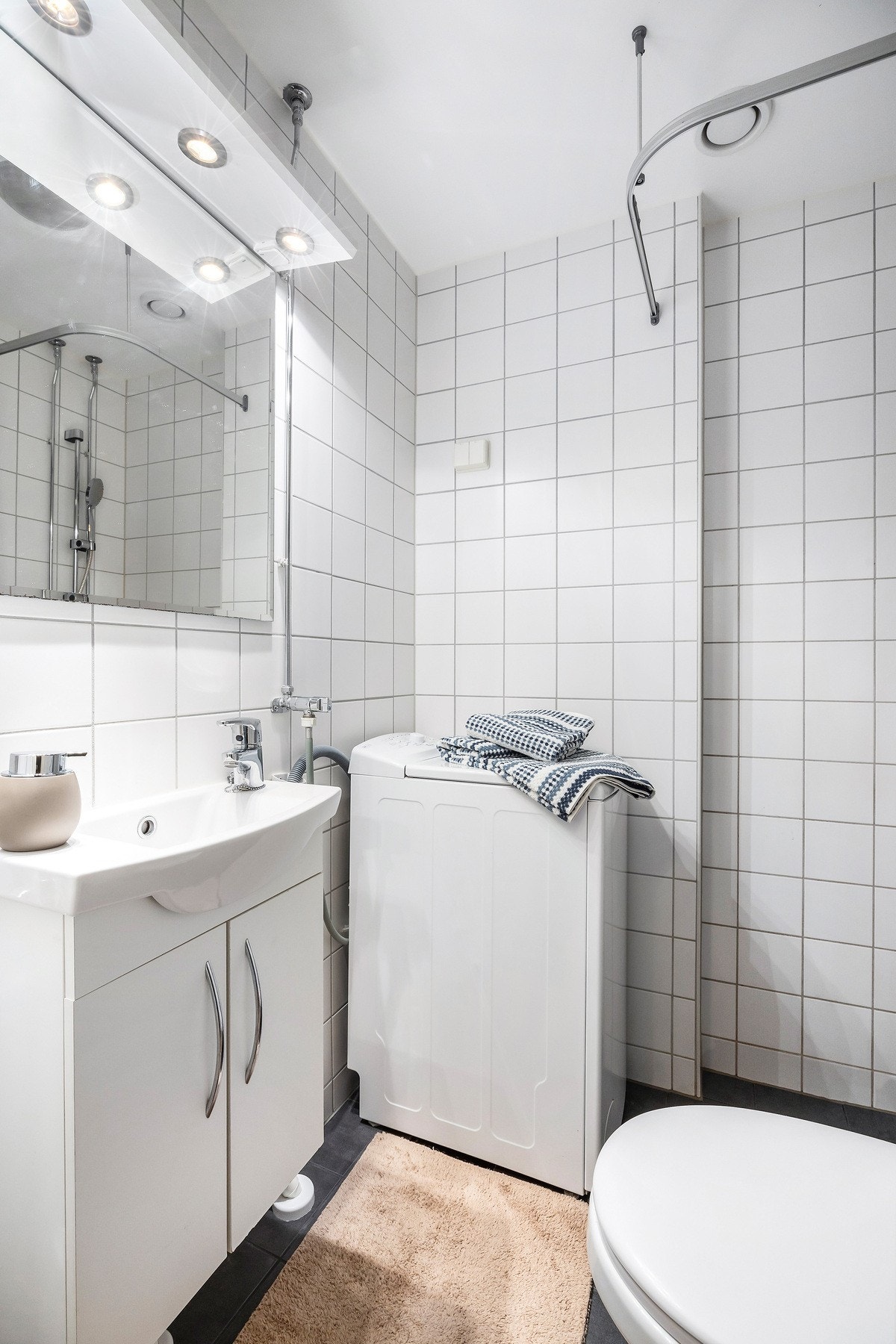 Flislagt baderom med dusj, servant og opplegg for vaskemaskin. Galleribilde