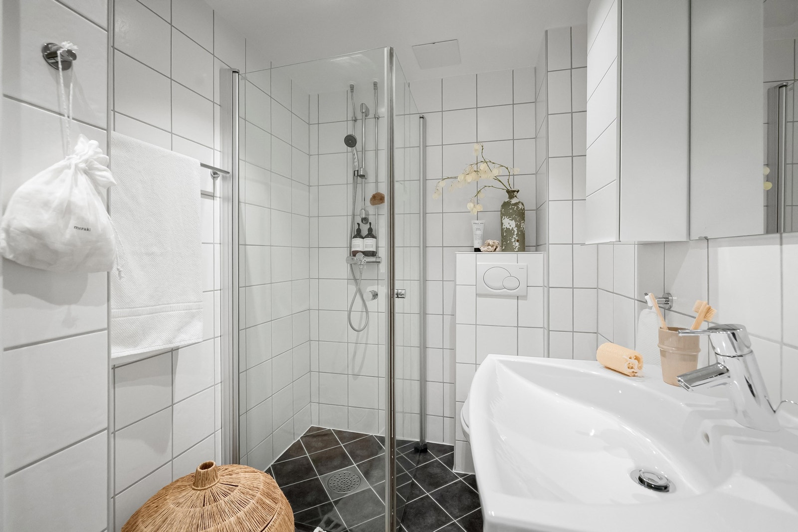 Badet har gulvvarme og inneholder veggmontert innredning med heldekkende servant og ett-greps blandebatteri, speil, dusjnisje med glassdører og vegghengt toalett. Galleribilde