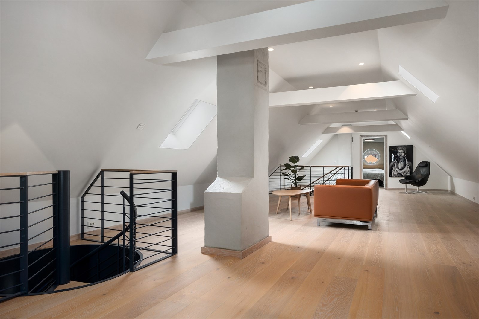 Loftsstuen er en egen opplevelse med høy takhøyde, synlige trebjelker og to dekorative trapper som gir rommet karakter. Galleribilde