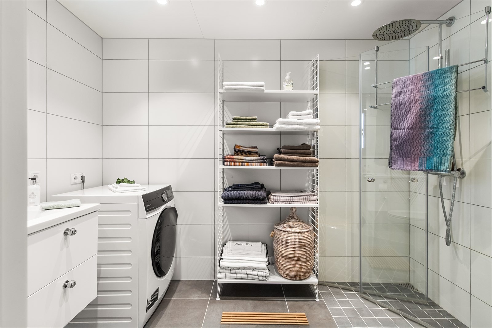 Det andre badet ligger i hendig tilknytning til entreen, og har hvite fliser på veggene, downlights i himlingen og grå fliser på gulv med gulvvarme. Installert regndusjhoder . Galleribilde