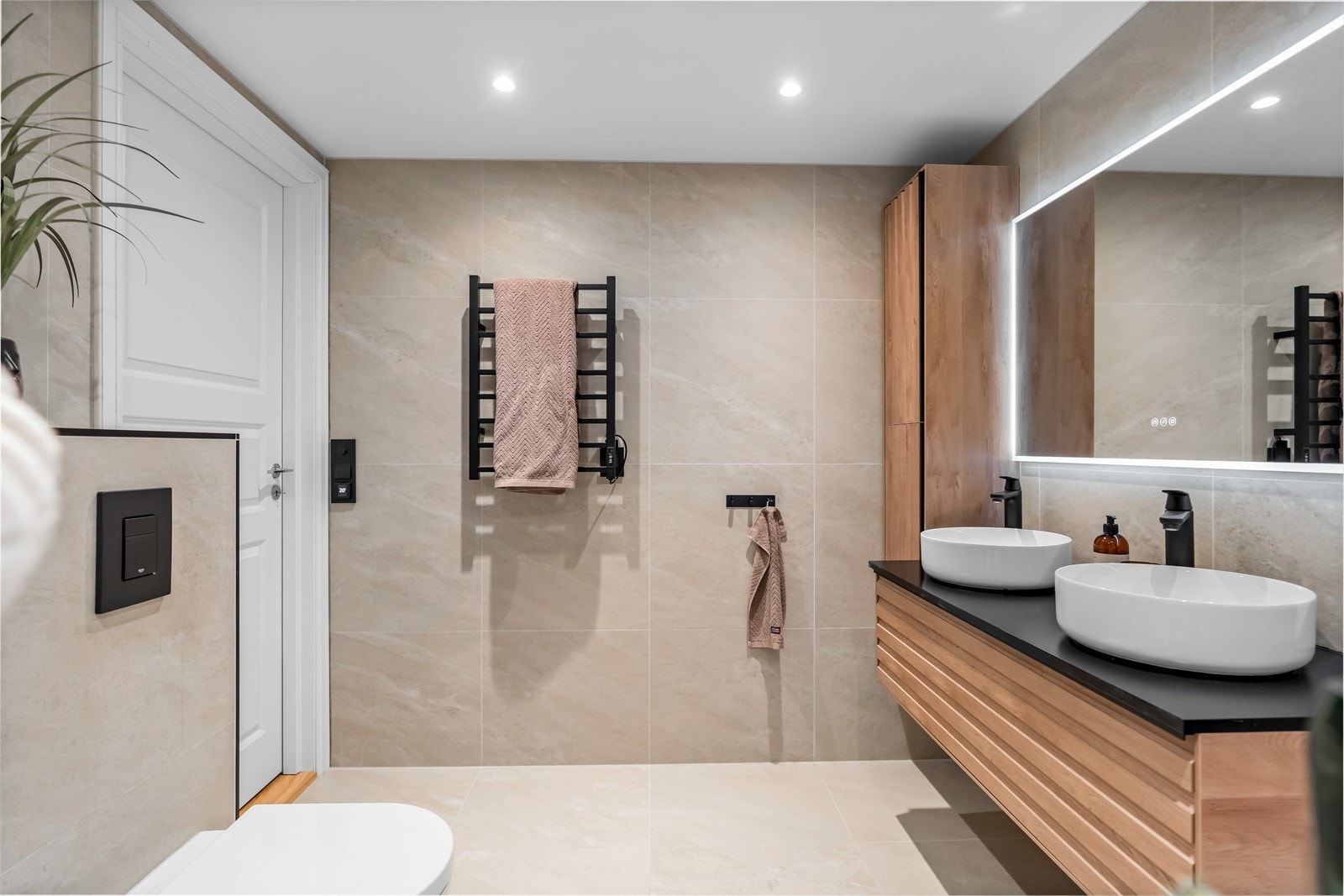 Badet er delikat innredet med beige gulv- og veggfliser, gulvvarme og downlights. Galleribilde