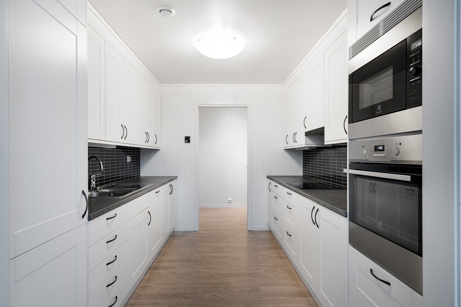 Kjøkkenet har innredning med glatte fronter og kantprofil, laminert benkeplate og sprutplater på vegg. Galleribilde