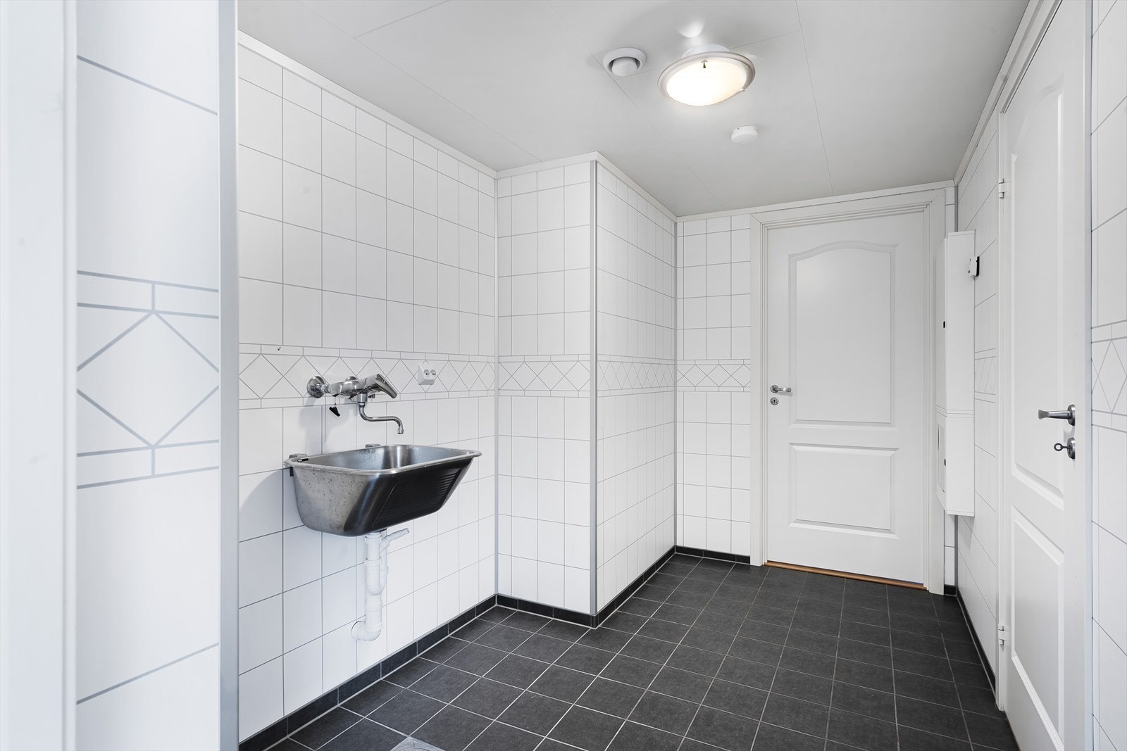 Rommet har skyllekar på vegg og opplegg for vaskemaskin. Galleribilde