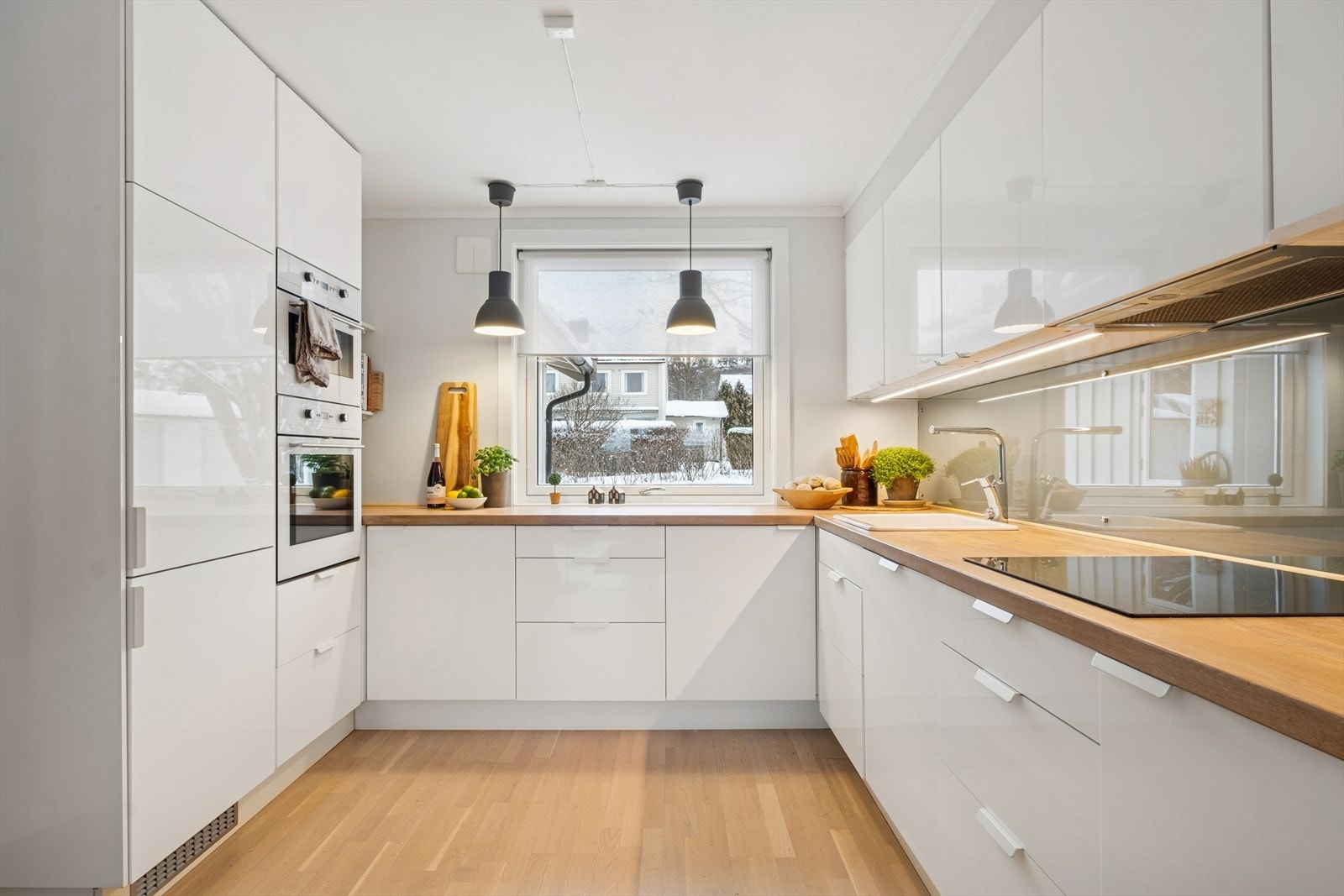 Kjøkkenet har en funksjonell innredning med hvite, glatte fronter og integrerte hvitevarer. Galleribilde