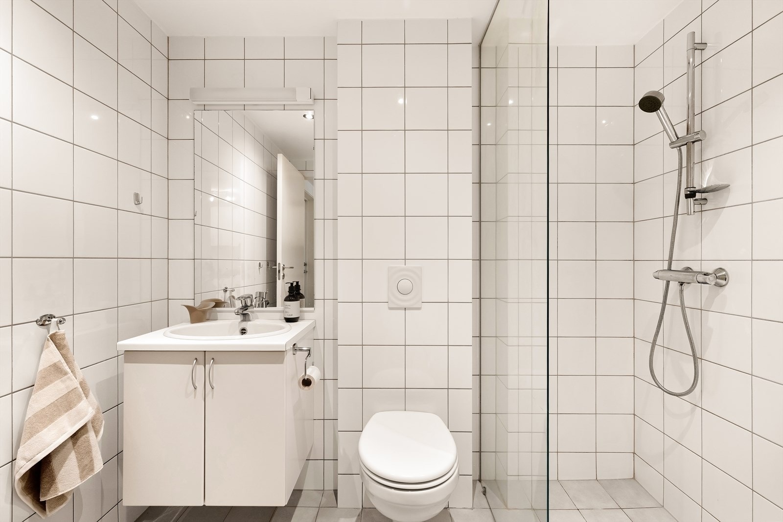 Flislagt bad med baderoms innredning, wc, dusjnisje og opplegg for vaskemaskin. Galleribilde