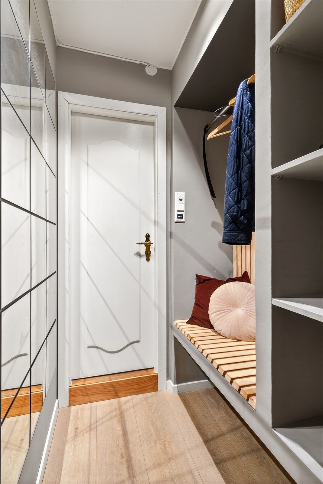 Man ankommer leiligheten inn til en romslig entré med god plass til oppbevaring av yttertøy og sko i garderobenisje med hyller og benk. Galleribilde