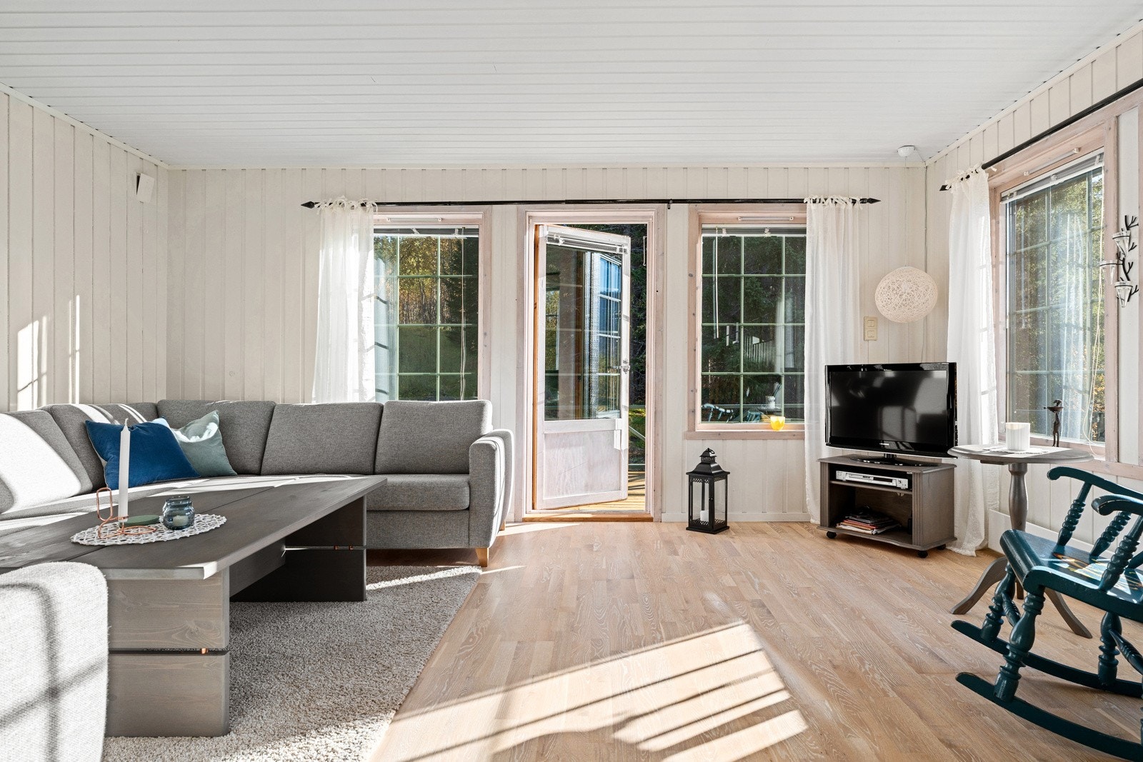Godt med lysinnslipp i stua og utgang til terrasse som strekker seg langs med boligen.