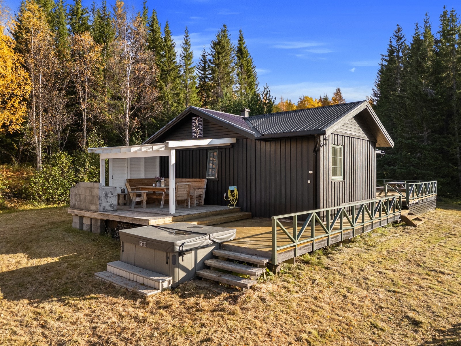 Utvendig terrasse med utgang fra stua med god plass til flere sosiale soner med utemøbler, planter og grill