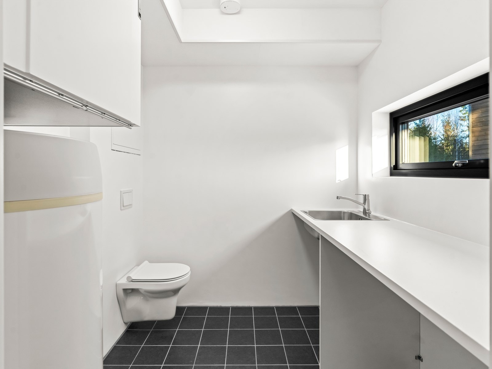 Vaskerommet er av god størrelse med lang benkeplate, vask, toalett og opplegg for vaskemaskin. Galleribilde