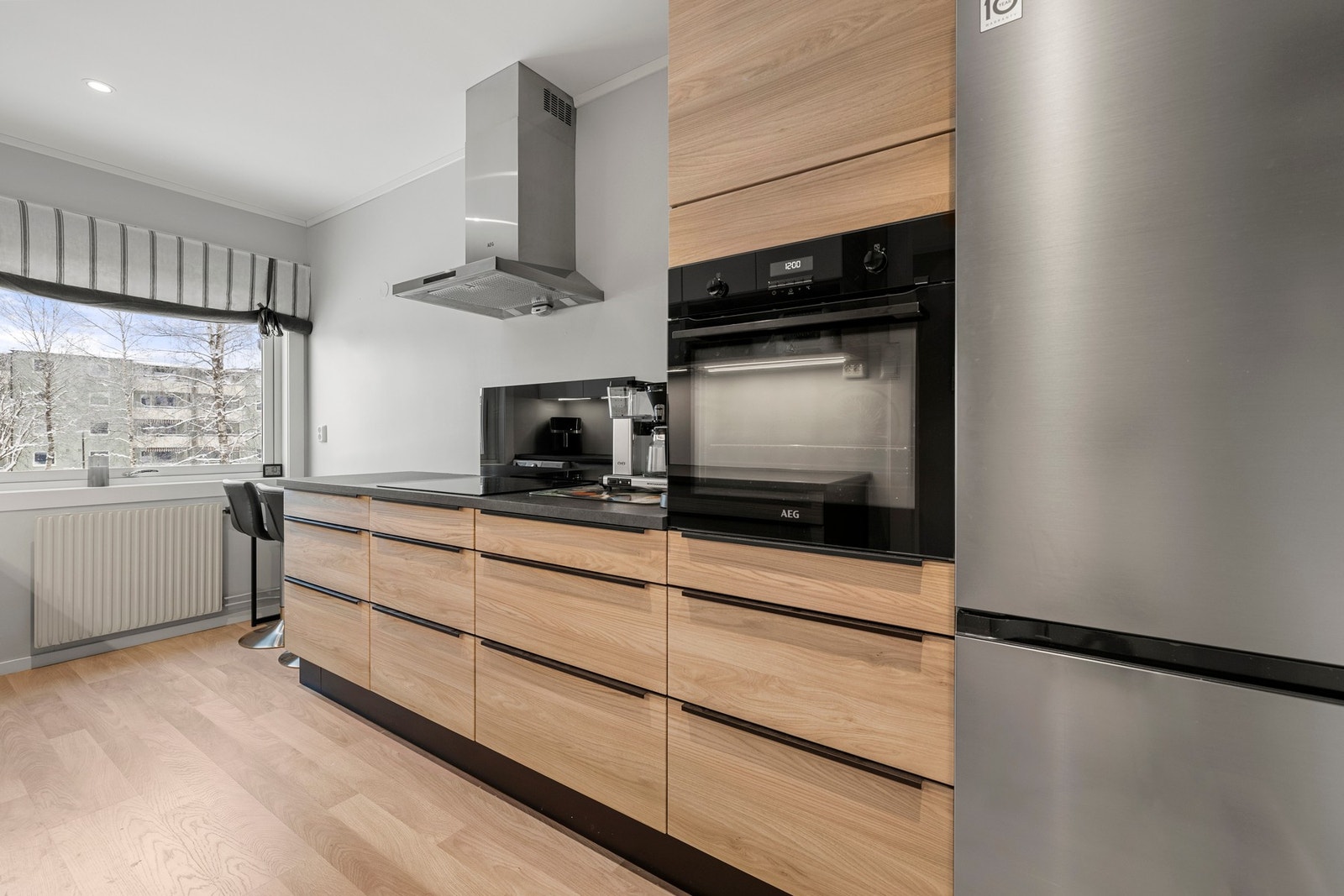 Innredningen har slette fronter, laminat benkeplate og belysning i underkant av overskap som gir både godt arbeidslys og et stilrent uttrykk. Galleribilde