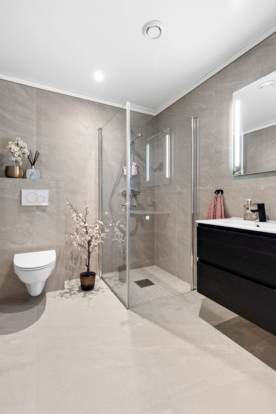 Speil med integrert belysning over servant. Stikkontakt på vegg. Nedsenket dusjsone med innfellbare glassdører. Dusjarmatur tilkoblet hånddusj. Galleribilde