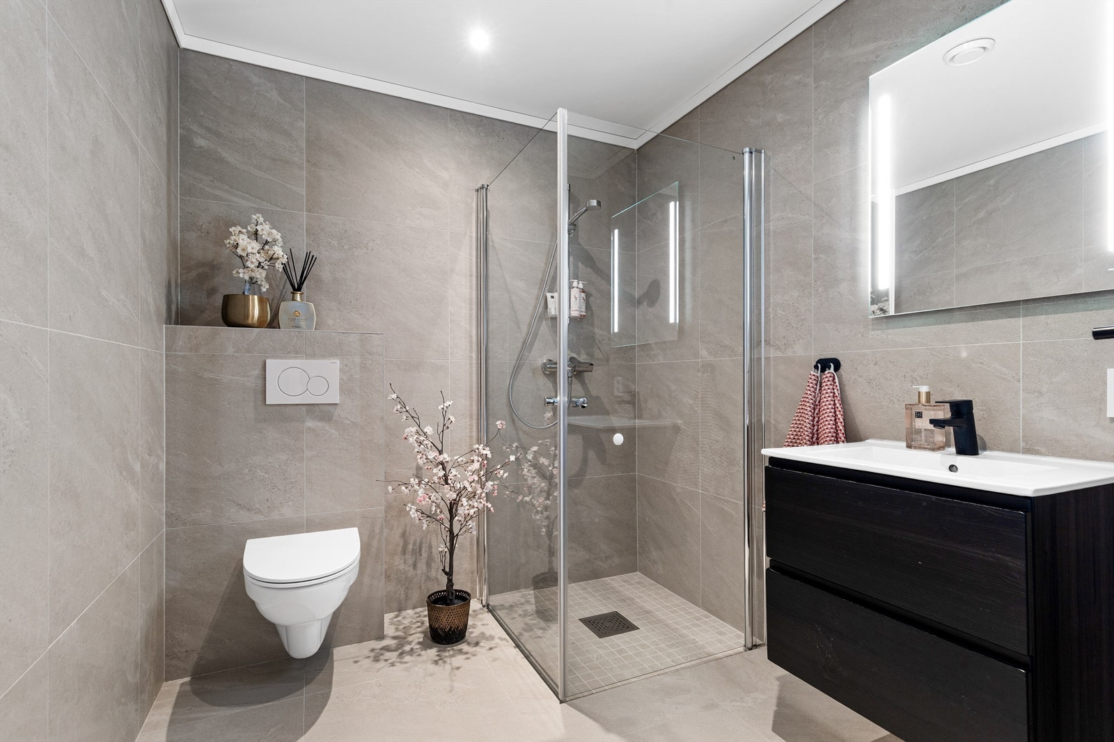 Bad fra byggeår. Flislagt gulv med varme og flislagte vegger. Nedsenket himling med downlights. Vegghengt servantskap med ovenpåliggende servant og ett-greps armatur. Galleribilde