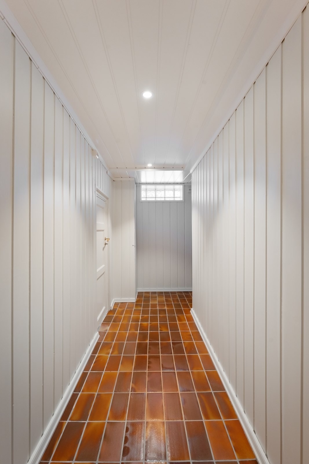 Kjellergangen har flislagt gulv og binder sammen rommene i underetasjen. Galleribilde