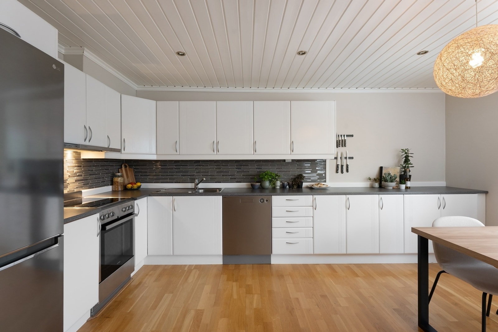 Romslig kjøkken med innredning med profilerte fronter og laminatbenkeplate. Galleribilde