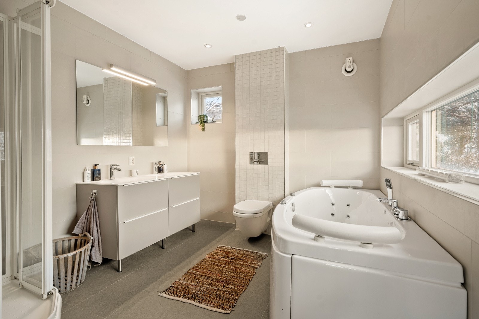 Baderommet i 2.etasje ligger i tilbygget fra 2012 og har lyse, behagelige farger som gir et moderne preg. Det er innredet med vegghengt klosett, servant nedfelt i innredningen, speil med lys, badekar og dusjkabinett. Galleribilde